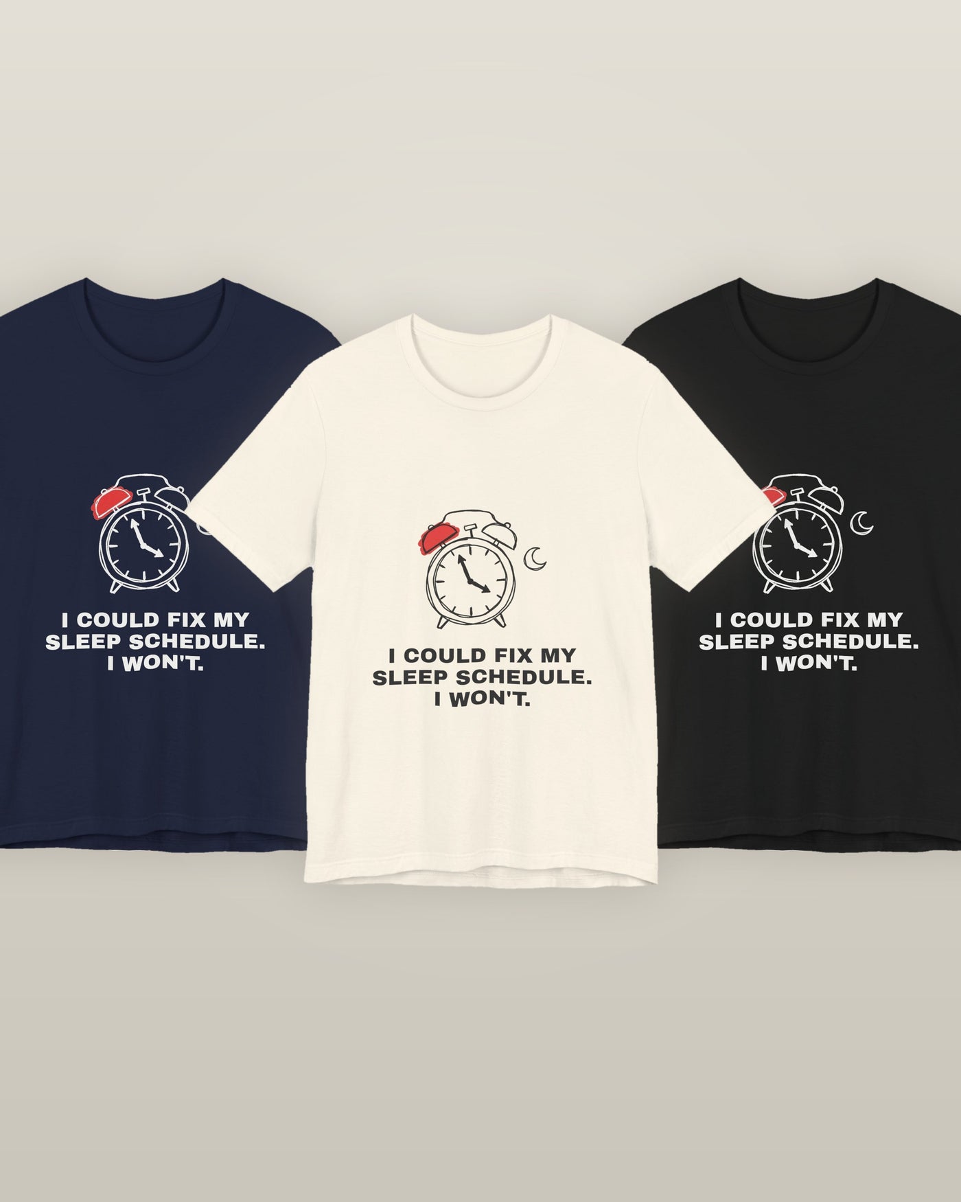 I could fix my sleep schedule. I won't. — an alarm clock at a very late hour beside a crescent moon, printed on a natural cream, navy and black cotton t-shirt, all three colourways together