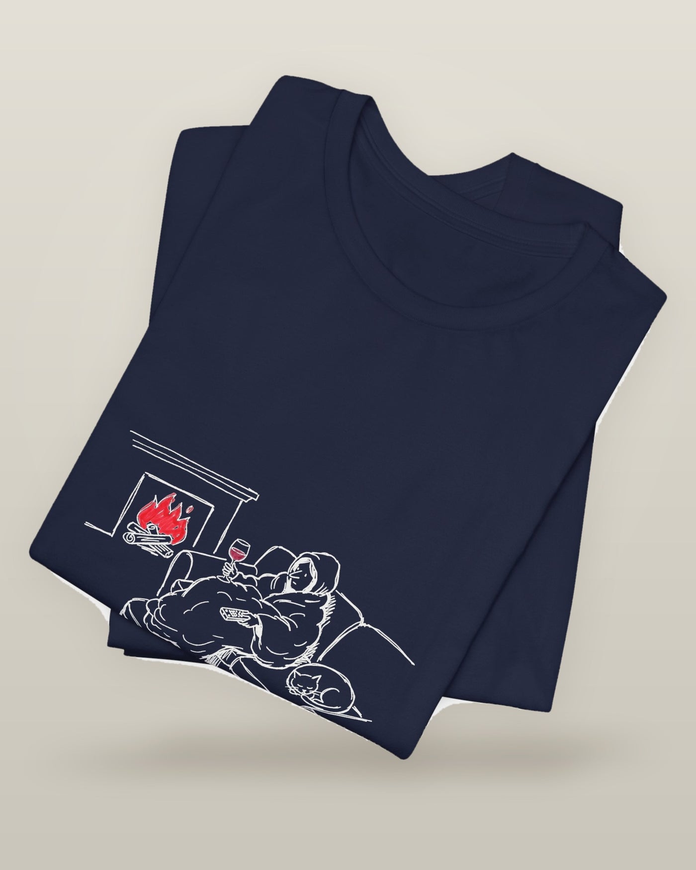 The night before a day off is more satisfying than the actual day off — a hooded figure under a blanket with wine, a remote, a sleeping cat and a lit fire, printed on a navy cotton t-shirt, folded