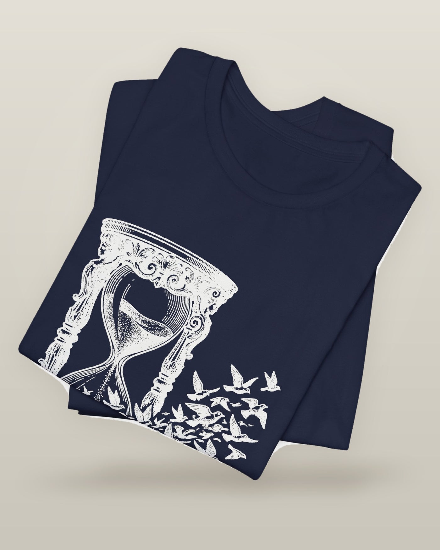The time I gave away — an hourglass whose falling sand becomes a flock of birds, printed on a navy cotton t-shirt, folded