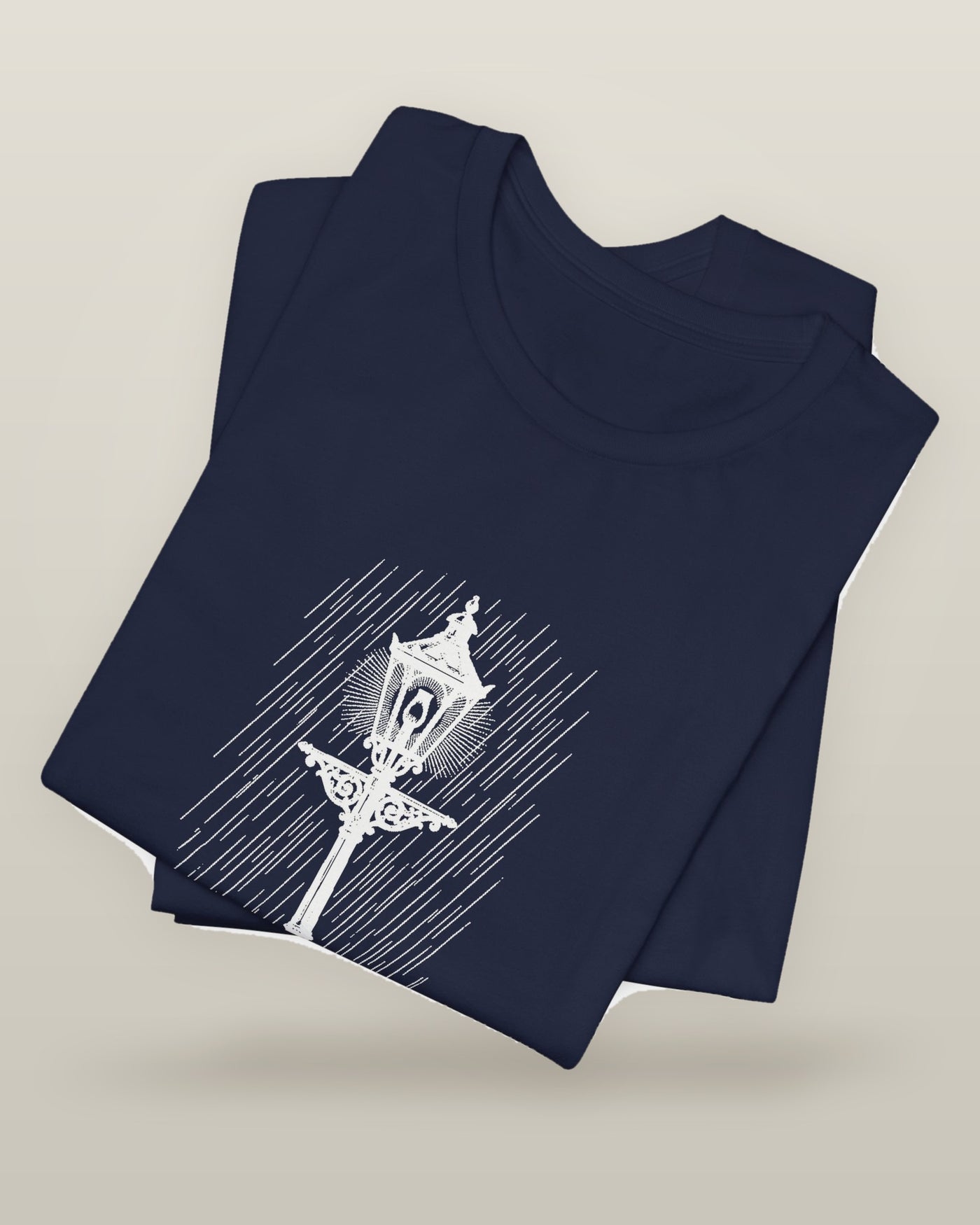 Still the only one awake — a cast-iron street lamp lit in fine rain, printed on a navy cotton t-shirt, folded