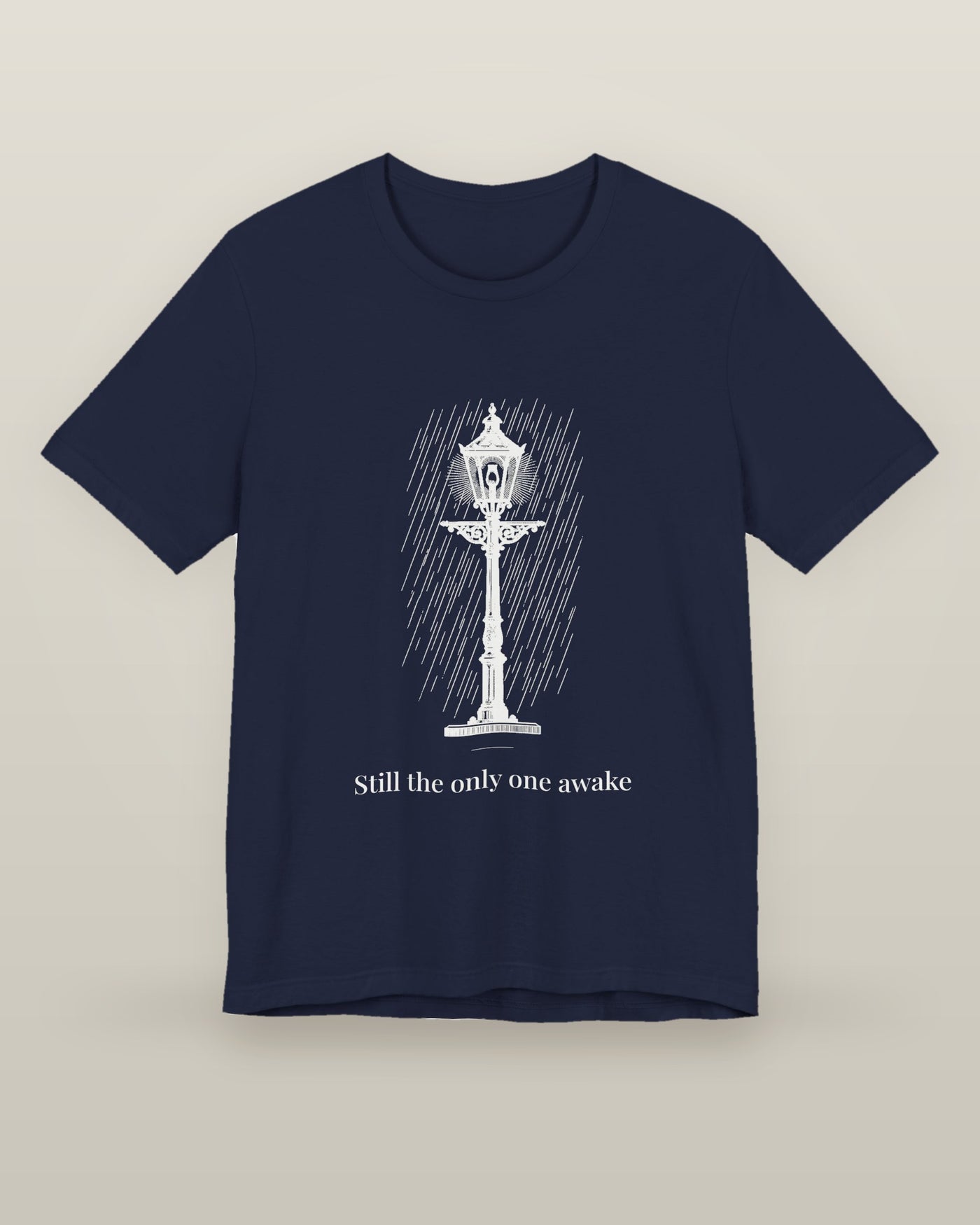 Still the only one awake — a cast-iron street lamp lit in fine rain, printed on a navy cotton t-shirt, front view