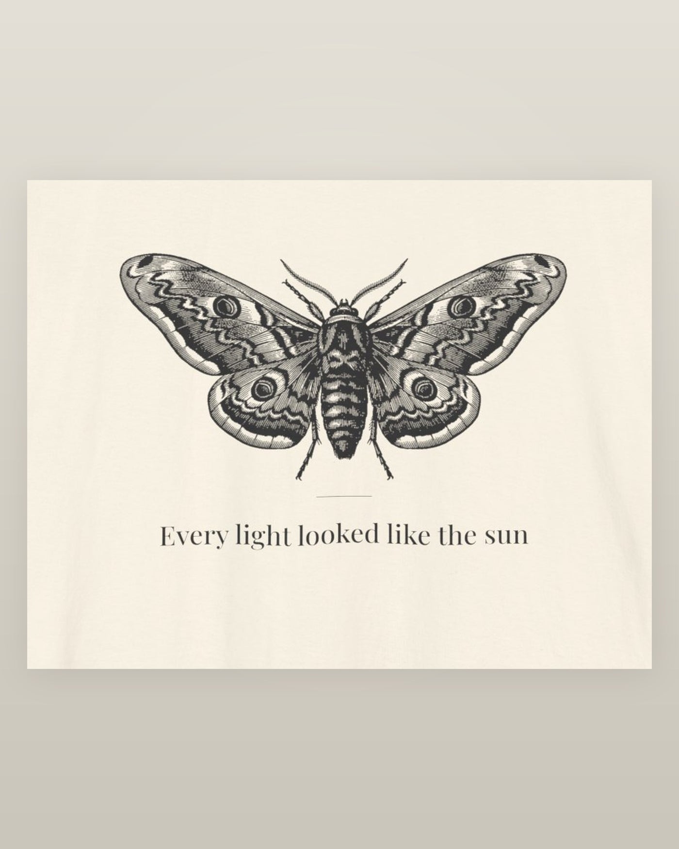 Every light looked like the sun — a moth specimen study, wings spread, printed on a natural cream cotton t-shirt, close detail of the print