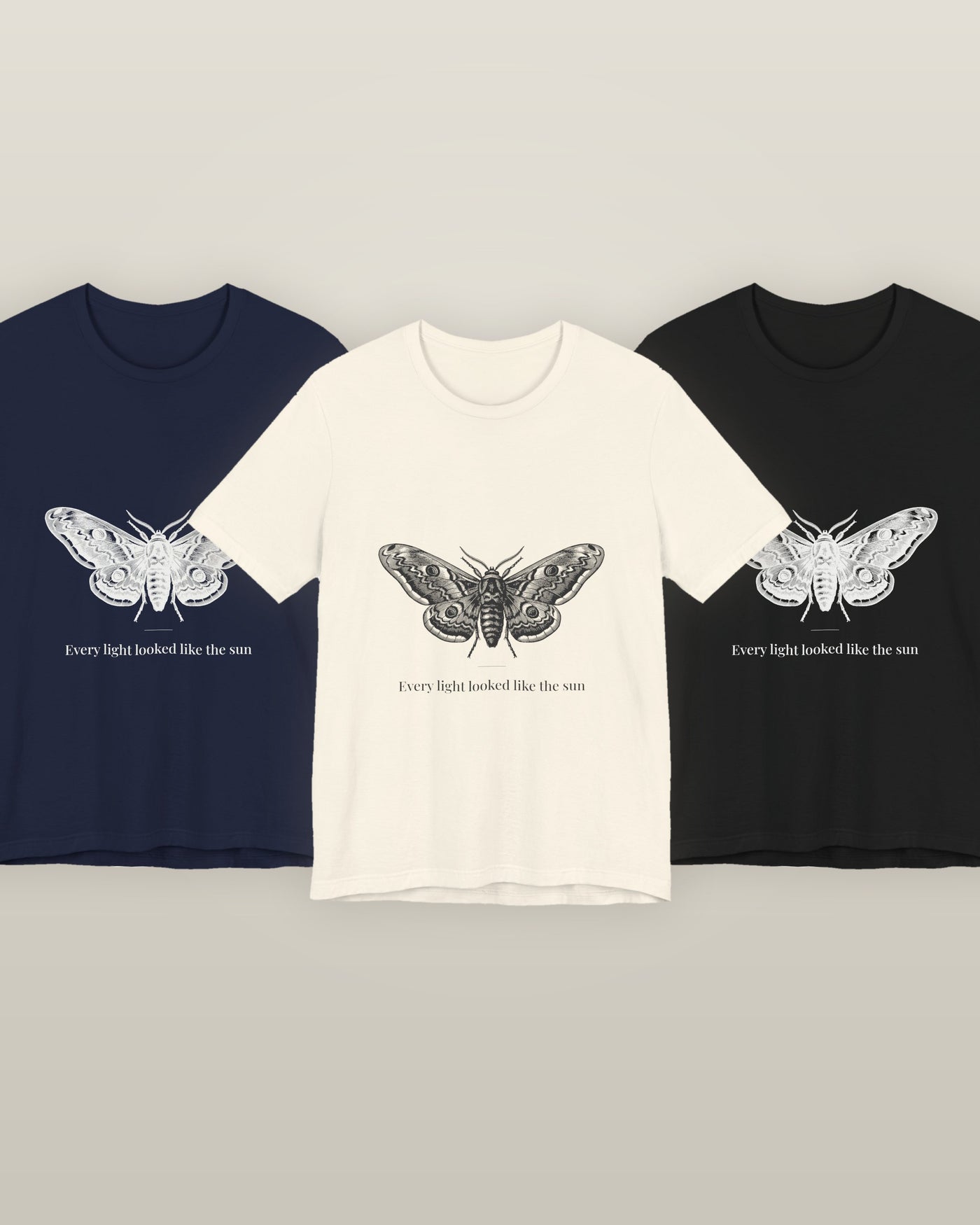 Every light looked like the sun — a moth specimen study, wings spread, printed on a natural cream, navy and black cotton t-shirt, all three colourways together
