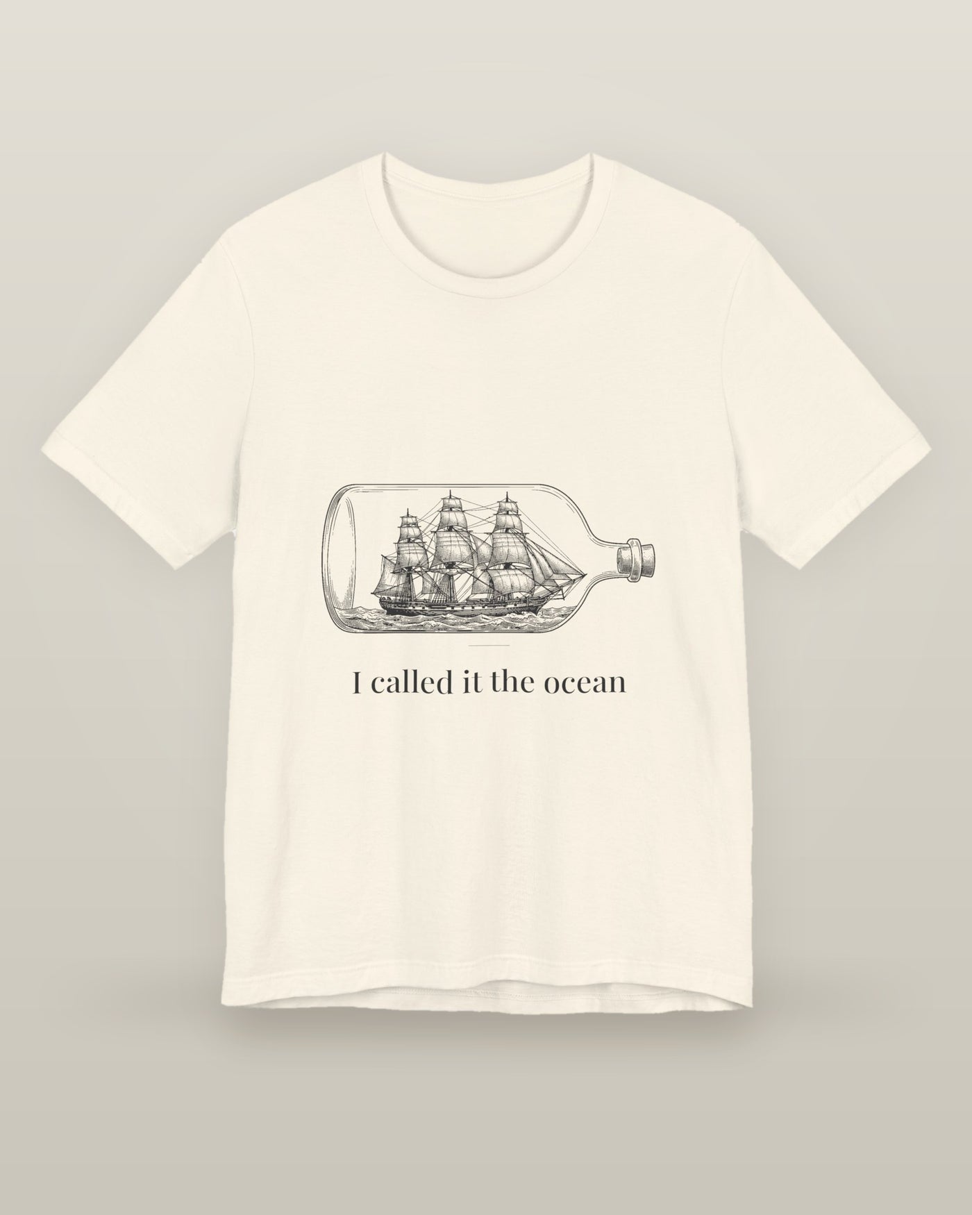 I called it the ocean — a full-rigged ship sealed in a glass bottle, printed on a natural cream cotton t-shirt, front view