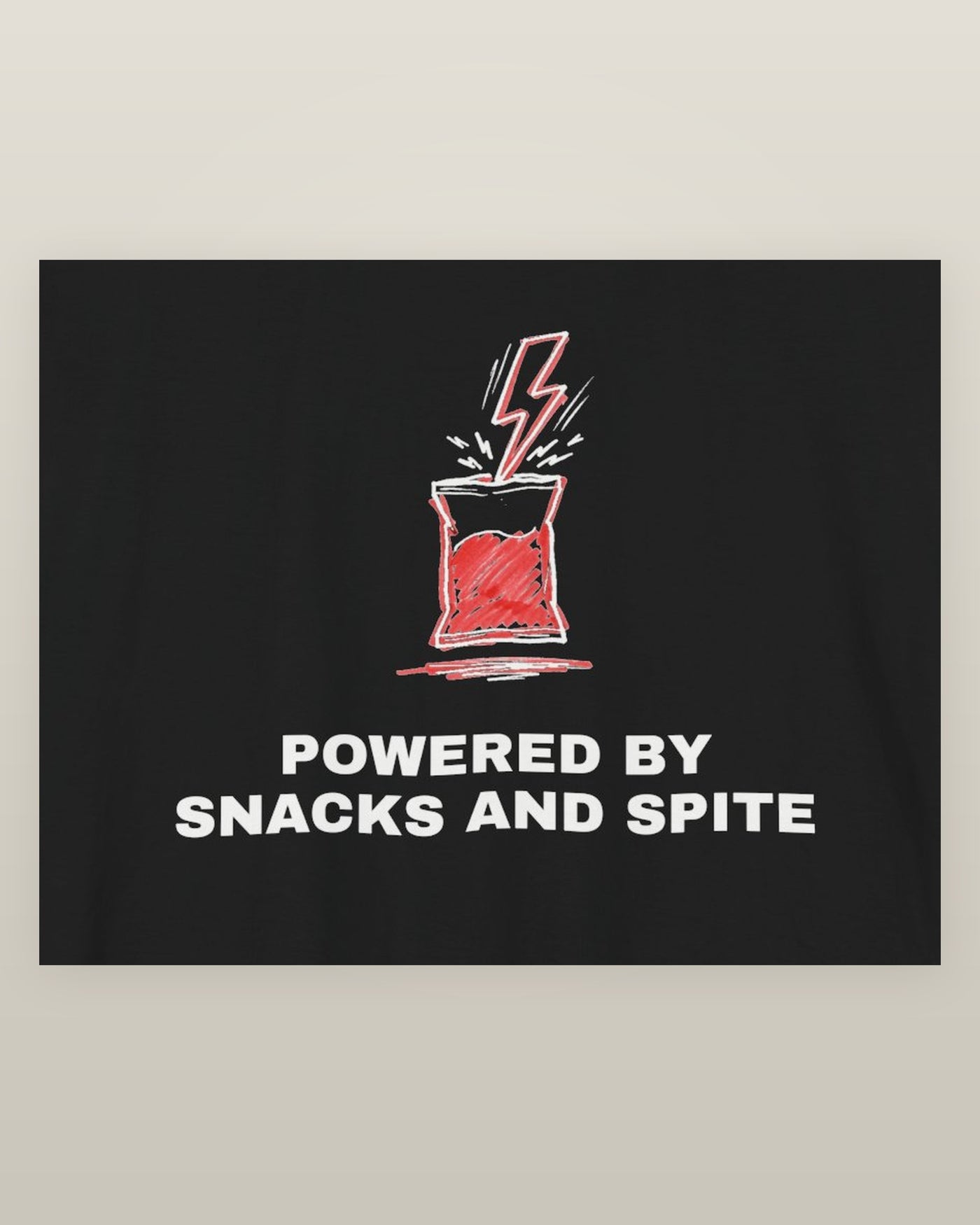 Powered by snacks and spite — a crisp packet struck by a lightning bolt, printed on a black cotton t-shirt, close detail of the print