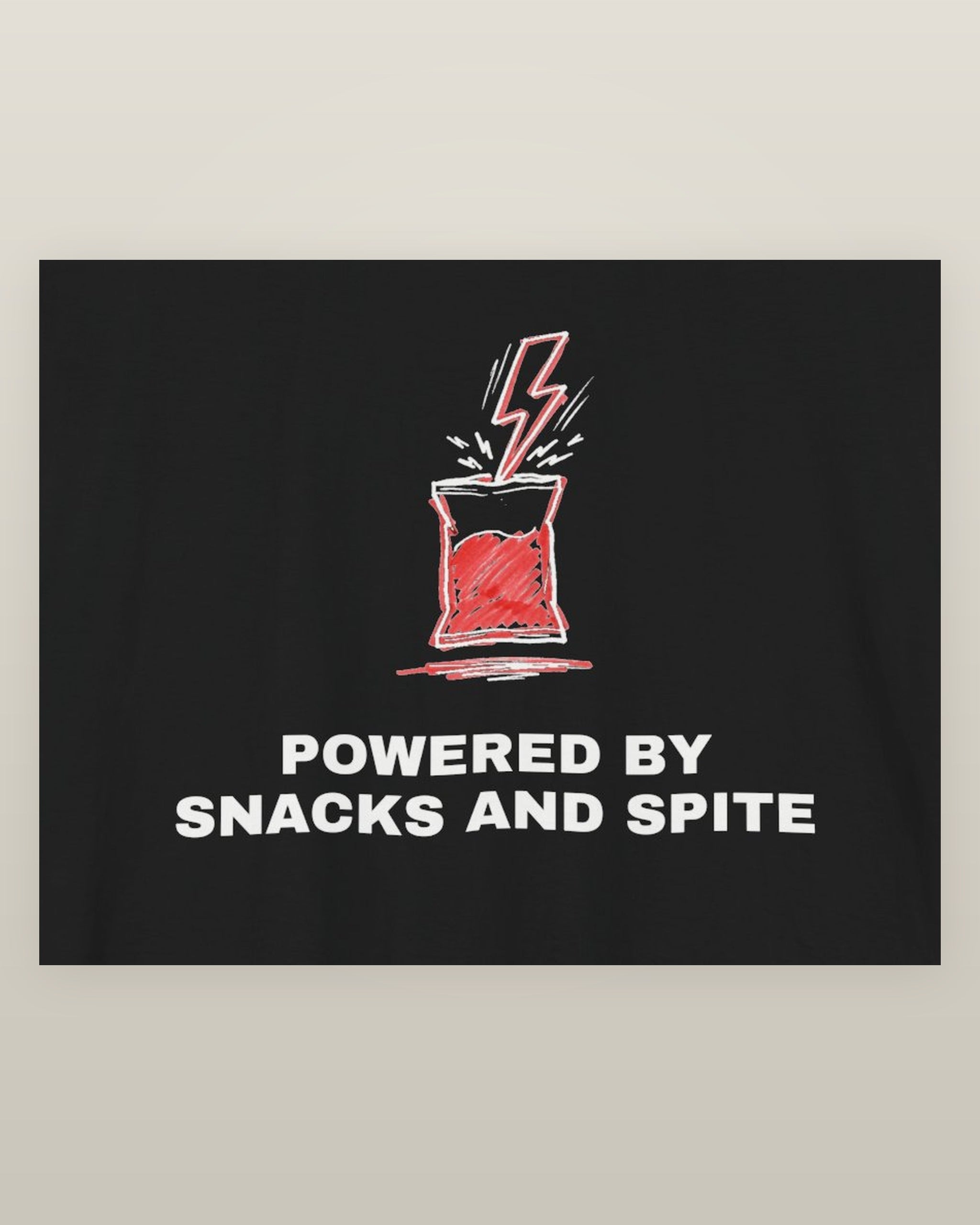 Powered by snacks and spite — a crisp packet struck by a lightning bolt, printed on a black cotton t-shirt, close detail of the print
