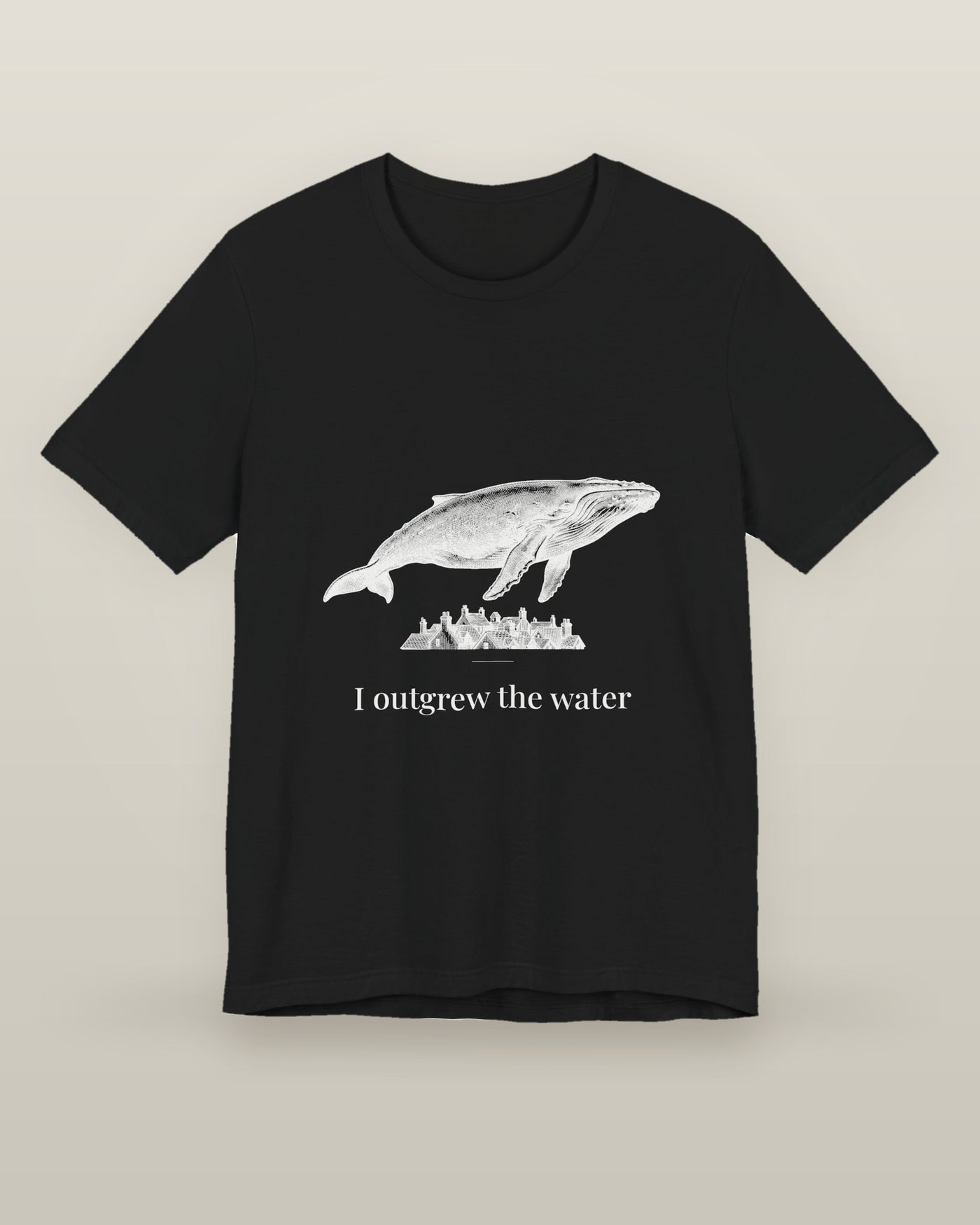 I outgrew the water — a humpback whale floating above rooftops, printed on a black cotton t-shirt, front view