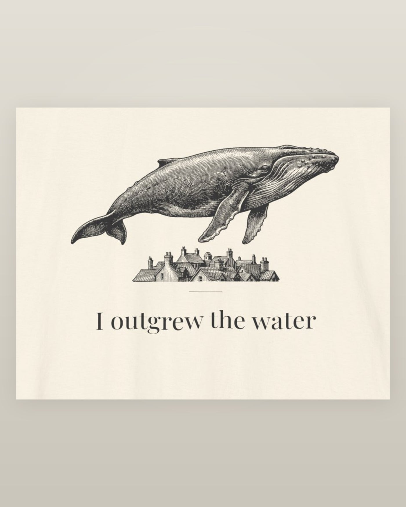 I outgrew the water — a humpback whale floating above rooftops, printed on a natural cream cotton t-shirt, close detail of the print