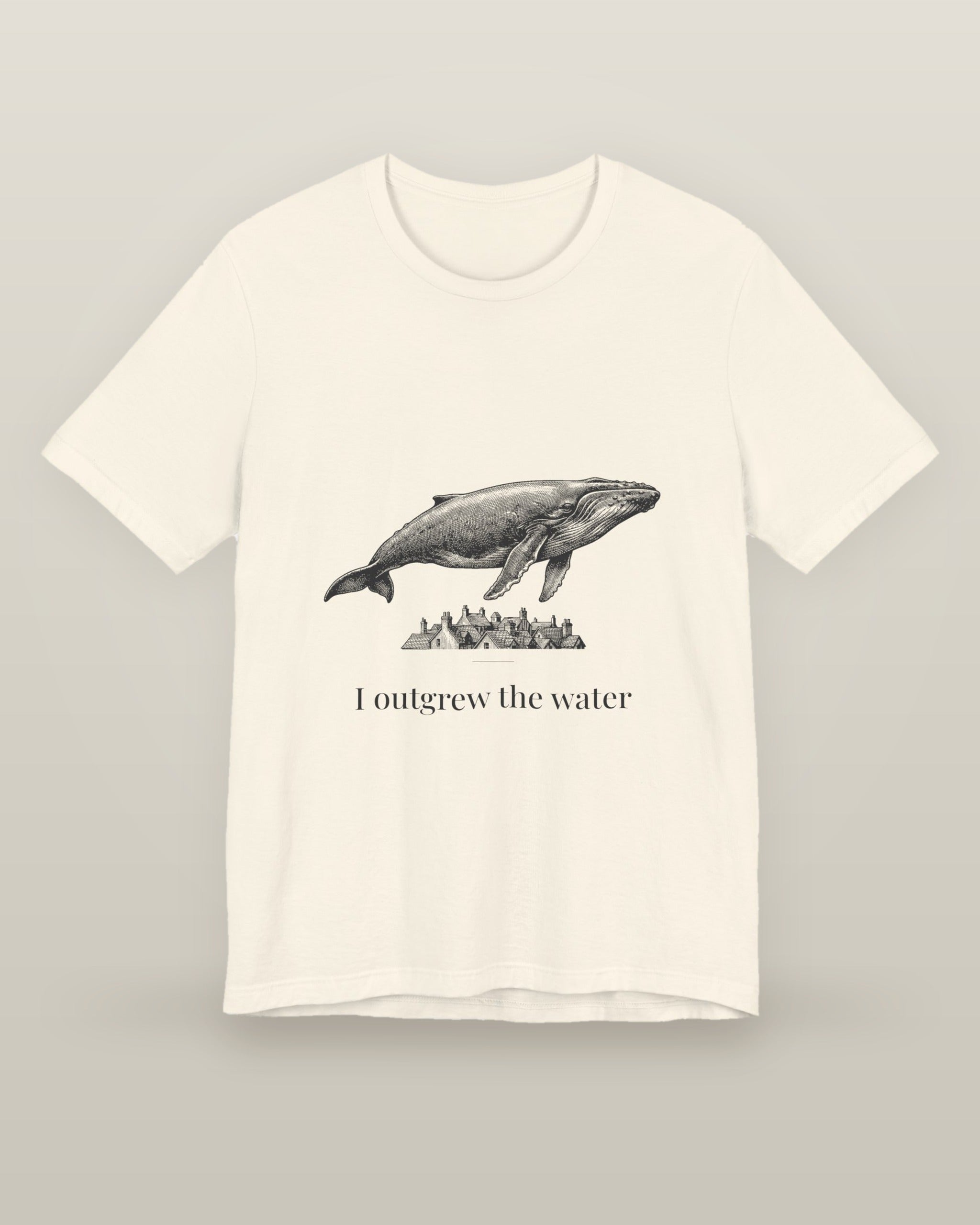 I outgrew the water — a humpback whale floating above rooftops, printed on a natural cream cotton t-shirt, front view